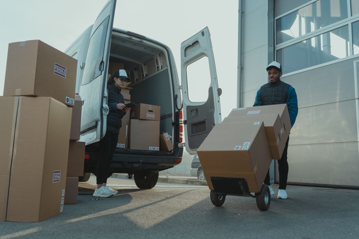 Operadores de courier cargando y entregando paquetes desde una furgoneta de reparto